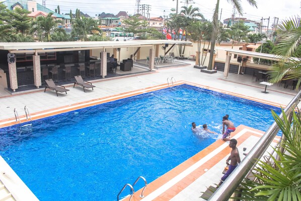 A swimming pool with lounge chairs and a covered area with tables and chairs. - Villa Park Hotels (Lagos)