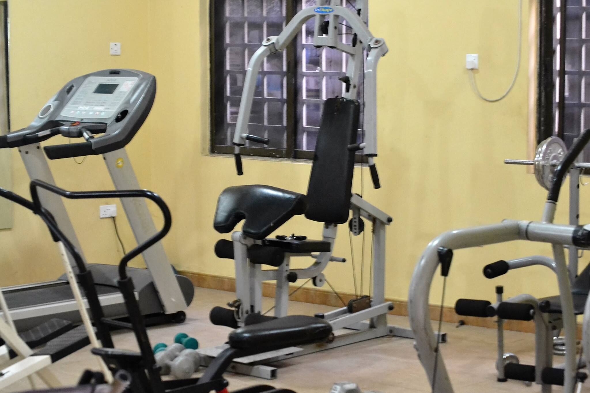 A gym with exercise equipment including a treadmill, weight bench, and various machines.