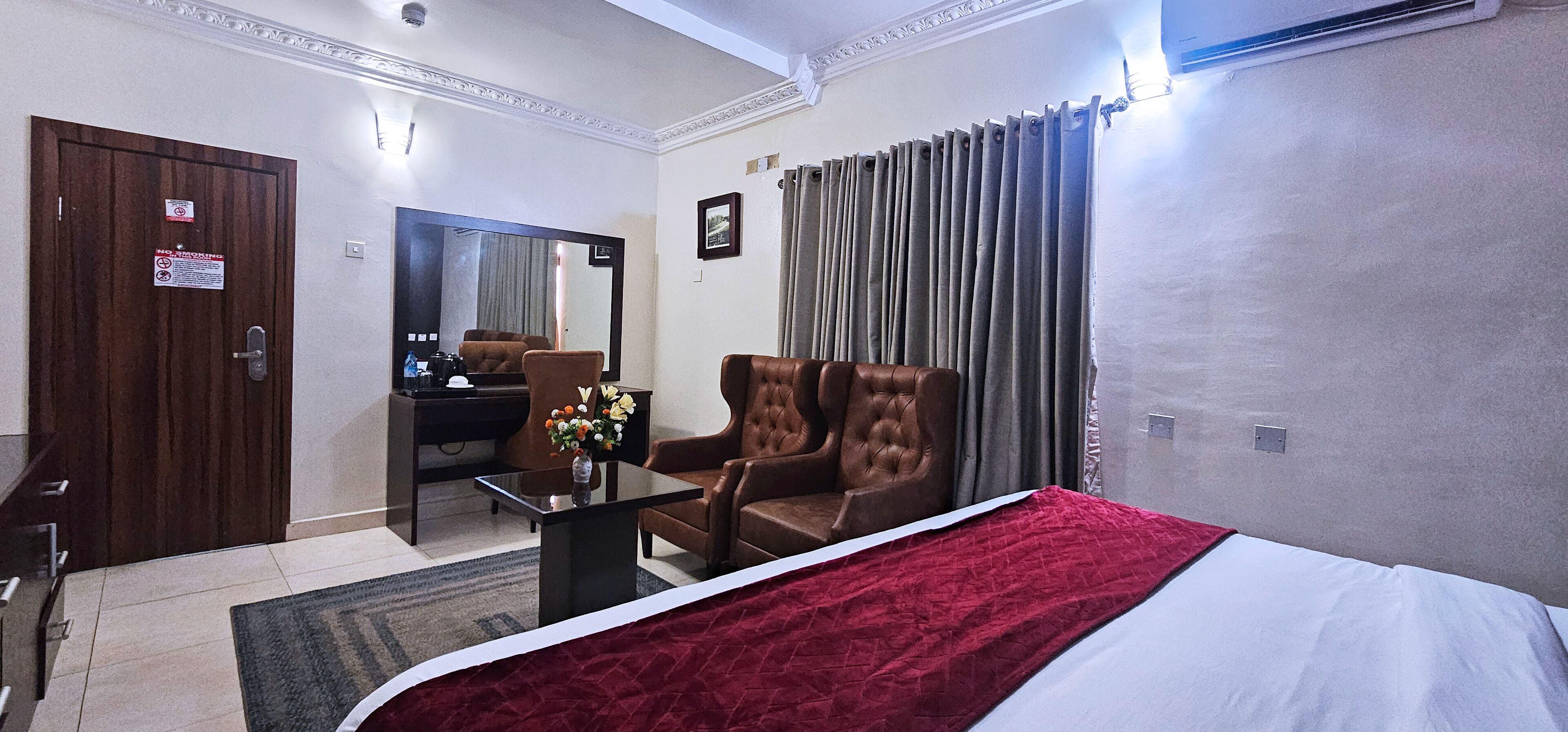Een hotelkamer met een bed, een bureau, een stoel, een spiegel en een gordijn.