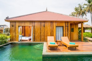 A wooden villa with a red tiled roof, a pool, and two lounge chairs with towels. - Floating Khmer Village Resort (Siem Reap)
