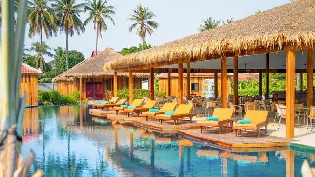 A poolside area with lounge chairs and thatched-roof structures. - Floating Khmer Village Resort (Siem Reap)