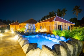 A wooden villa with a swimming pool, surrounded by rocks and palm trees. - Floating Khmer Village Resort (Siem Reap)