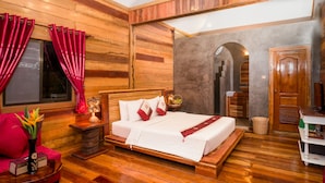 A wooden-paneled room with a bed, red curtains, a small table with a vase, and a wooden bench. - Floating Khmer Village Resort (Siem Reap)