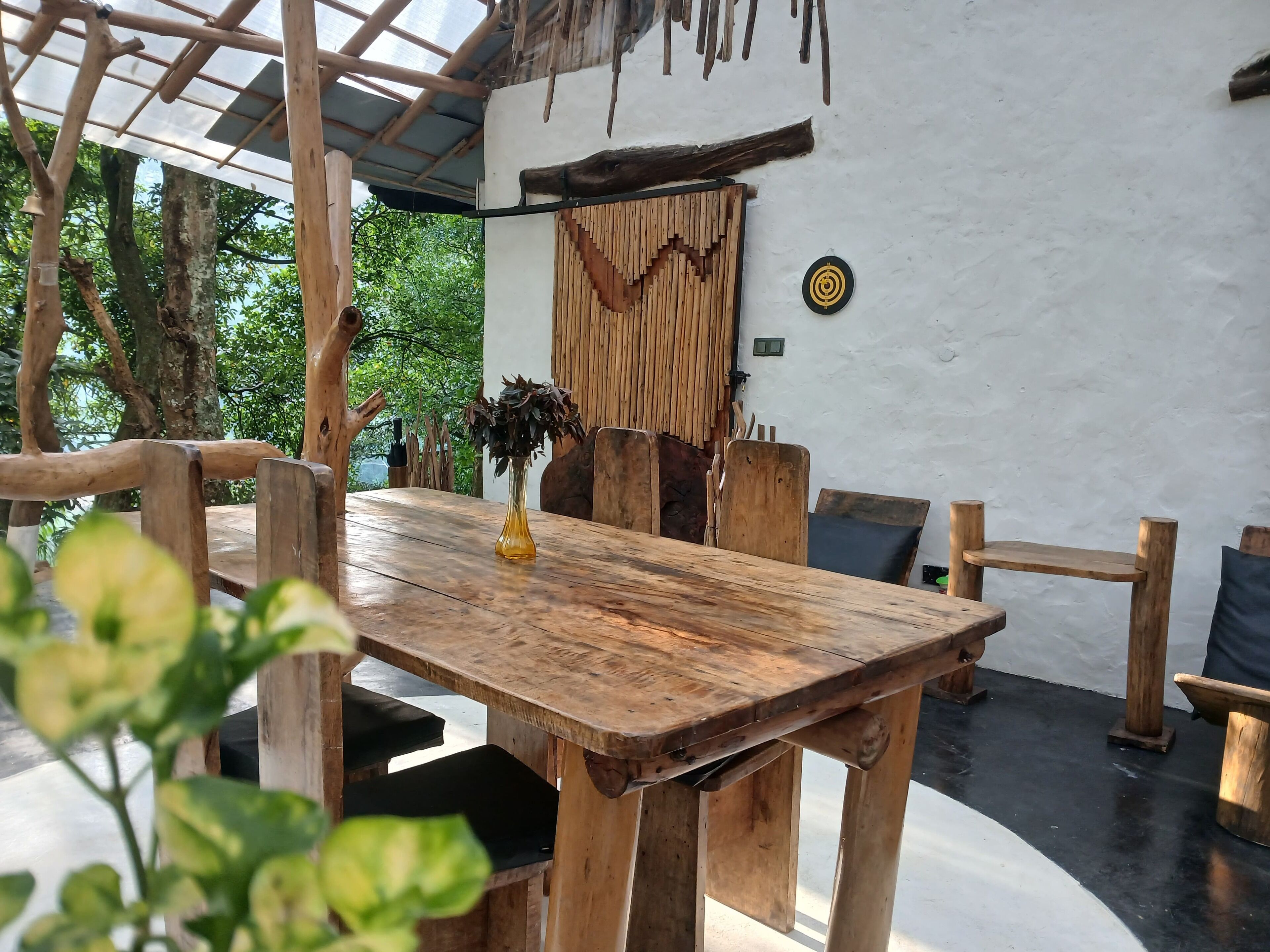 A rustic wooden dining table with benches, a hanging wooden decoration, and a potted plant.