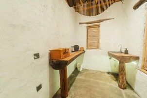 Un baño rústico con un banco de madera, un lavamanos y una ventana.
