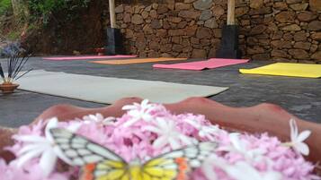 A stone wall, yoga mats, and a butterfly on flowers.