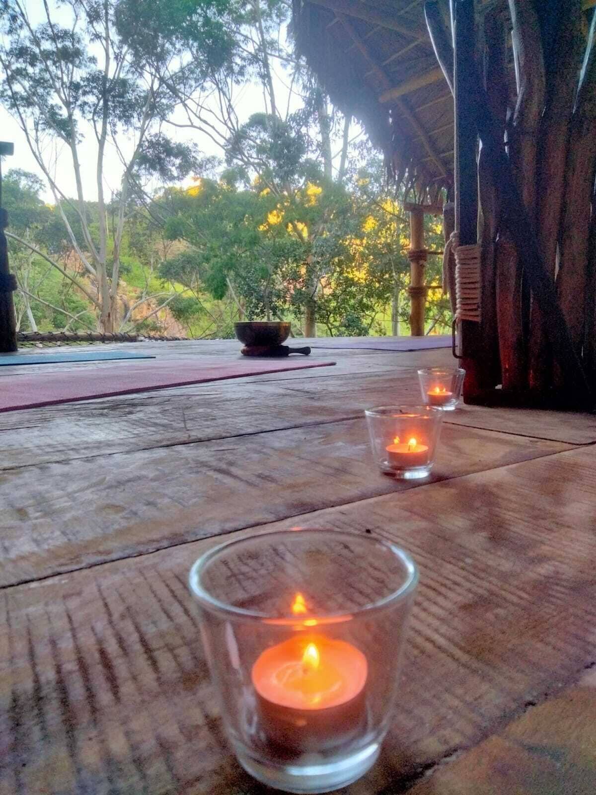 Una mesa de madera con dos velas encendidas en recipientes de vidrio y un cuenco de piedra.