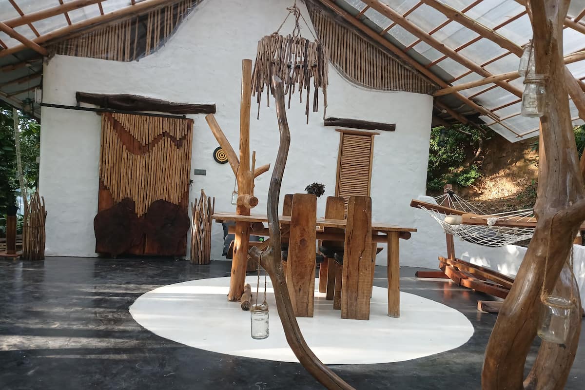 A rustic wooden interior with a round table, chairs, and a hanging light fixture.