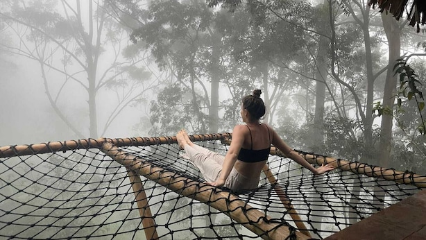 A person sitting on a hammock in a forested area with a thatched roof structure nearby. - Ella Retreat Hotel (Ella)