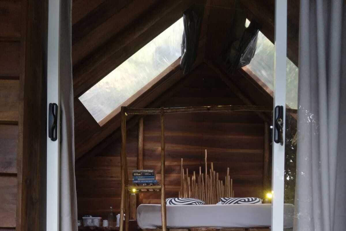 A cozy attic bedroom with a bunk bed, wooden beams, and a skylight.