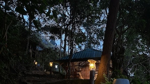A stone pathway leading to a rustic wooden structure with a metal roof, surrounded by dense foliage. - Ella Retreat Hotel (Ella)
