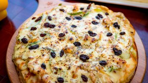 A pizza with visible toppings on a wooden board. - Deluxe Double Room - Free breakfast (Kok chock commune)