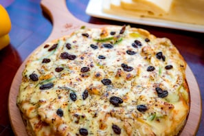 Pizza mit sichtbaren Belägen auf einer Holzplatte.