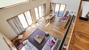 A spacious living area with a wooden floor, large windows, a dining table, and a sofa. - (11) Gud Jard Chalet Großer Bär, Cat. FamilienZeit - Design holiday home Großer Bär (Pellworm)