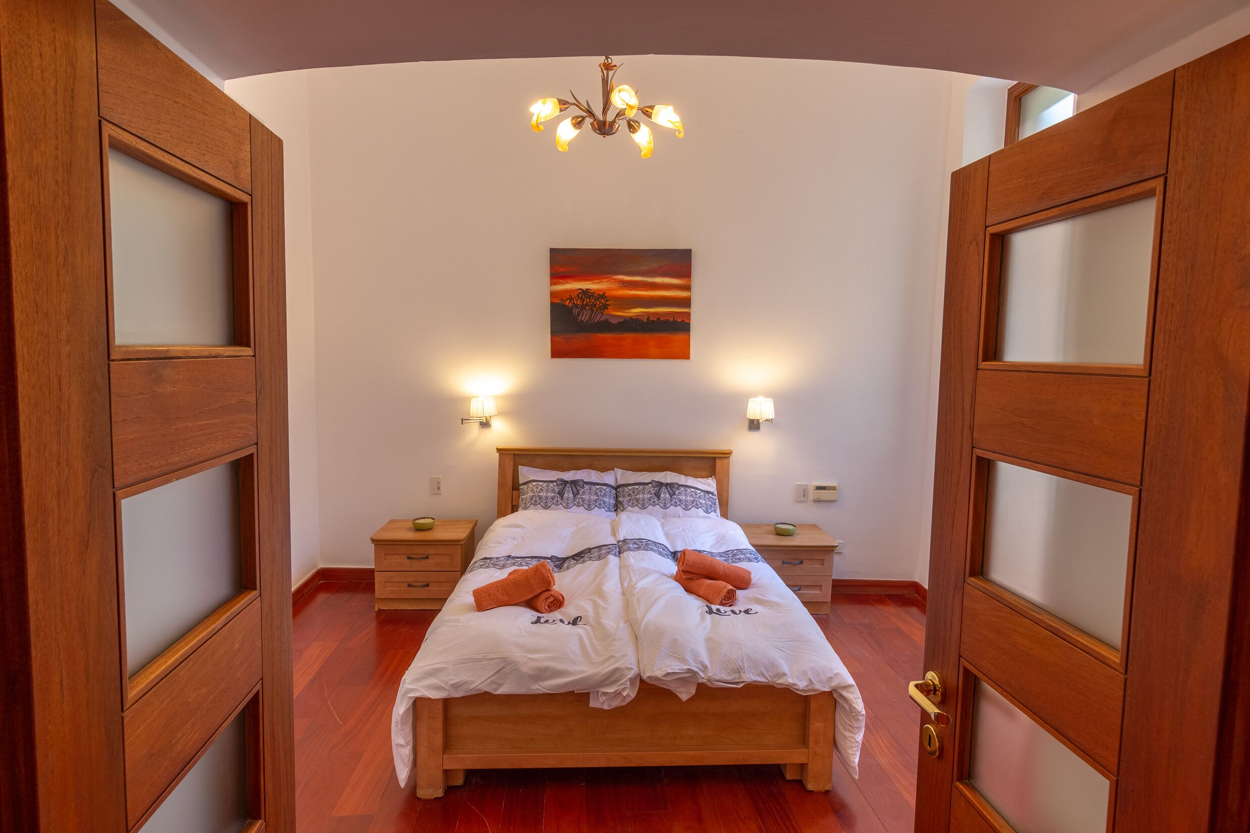Ein Schlafzimmer mit einem Holzbett, einem Bild an der Wand und zwei Nachttischlampen.