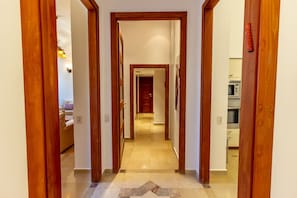Um corredor com portas de madeira que dão para uma sala de estar e uma cozinha.