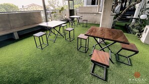 An outdoor seating area with tables and chairs, surrounded by greenery and concrete structures. - Haggai - Tourist Bangalow (Colombo)