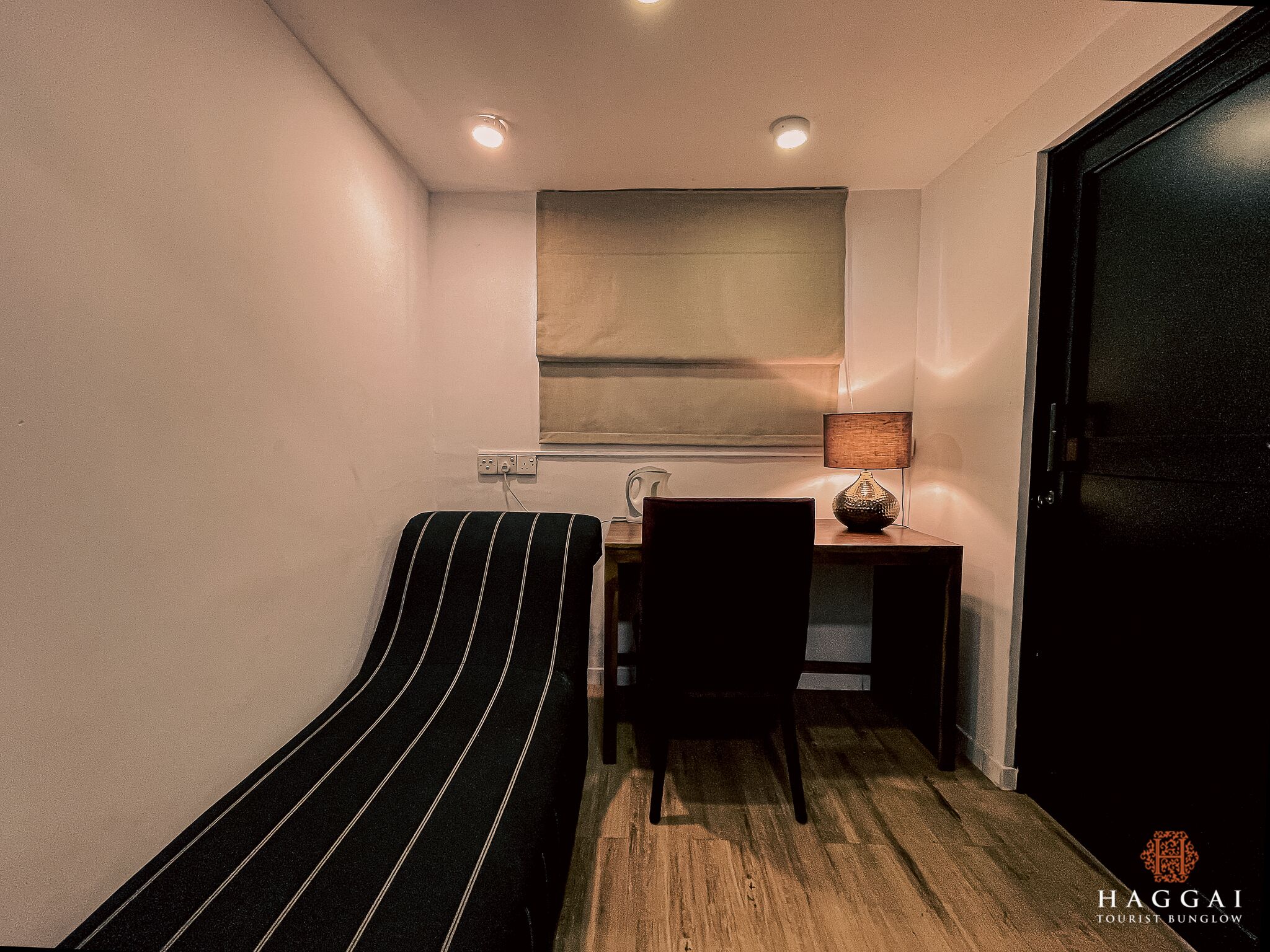 Habitación pequeña con cama individual, un escritorio, una silla y ventana con cortina.