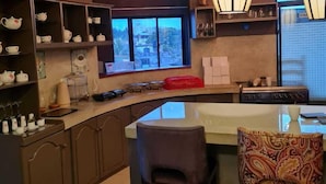 A modern kitchen with a large island, bar stools, and a view of the city through a large window. - Haggai - Tourist Bangalow (Colombo)