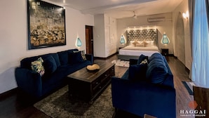 A modern hotel room with a large bed, a sofa, a coffee table, and a painting on the wall. - Haggai - Tourist Bangalow (Colombo)