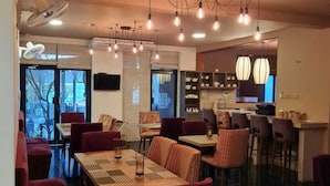 A restaurant with multiple dining tables and chairs, a bar area, and pendant lighting. - Haggai - Tourist Bangalow (Colombo)