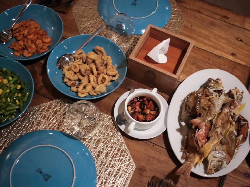 A table set with various dishes, including seafood and vegetables, on a woven placemat.