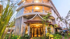 Un immeuble à plusieurs étages doté d’une façade incurvée, de balcons et d’une entrée bien éclairée.
