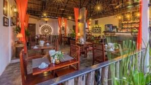 Un restaurant avec des tables et des chaises en bois, un toit de chaume et un comptoir bien visible.