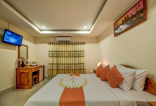 A hotel room with a bed, a desk, a television, curtains, and a painting on the wall. - Deluxe Double Room - breakfast (Kok chock commune)