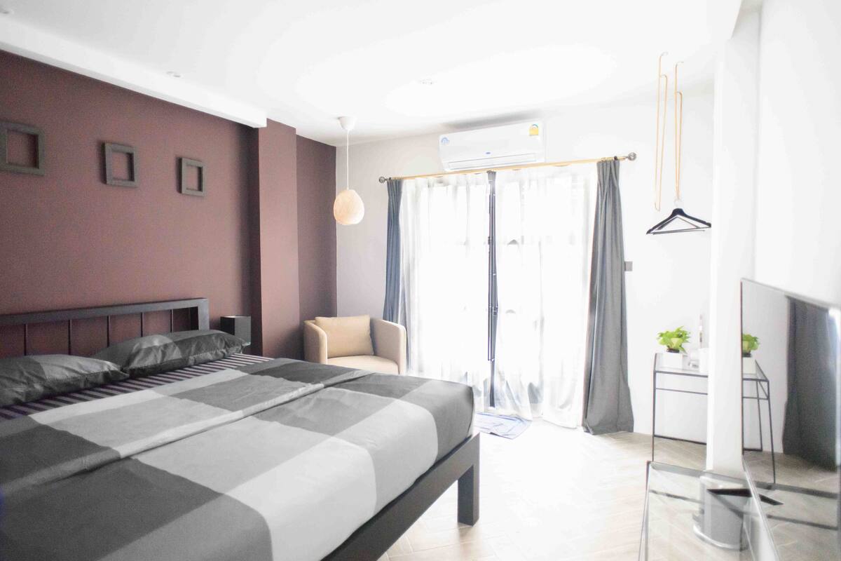 Un dormitorio moderno con una cama grande, una pequeña zona de estar y vistas al exterior.