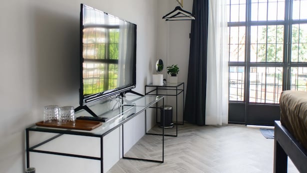 A modern living room with a flat-screen TV, a glass coffee table, a potted plant, and a large window with curtains. - 87 Oldtown @ River Pier (Bangkok)