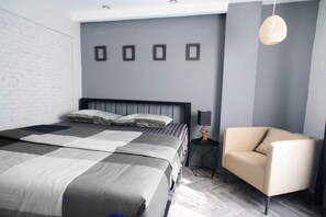 A modern bedroom with a large bed, a side table with a lamp, and a chair.