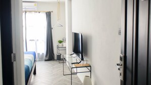 A modern hotel room with a bed, a TV, a desk, and a large window with curtains. - 87 Oldtown @ River Pier (Bangkok)