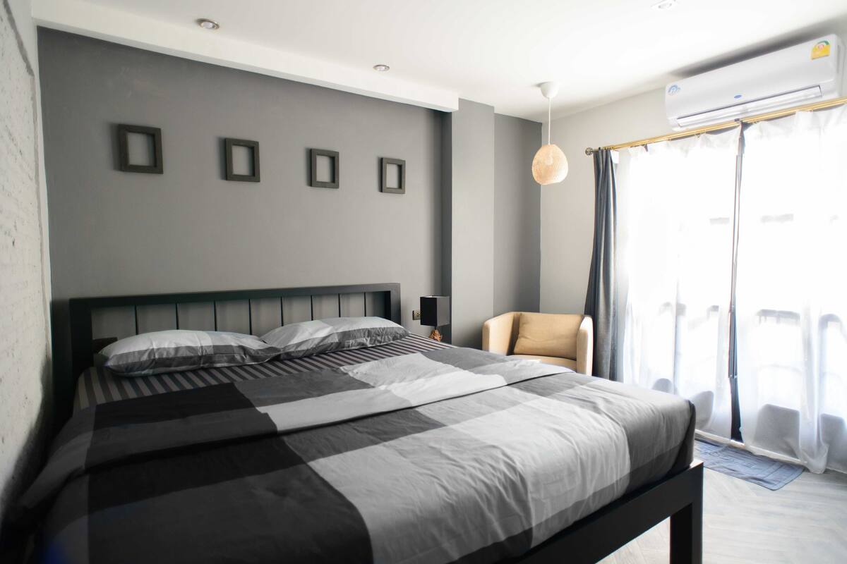 Un dormitorio moderno con una cama grande, una silla y un ventilador de techo.