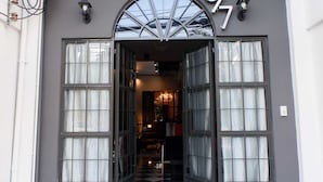 A building entrance with a large arched doorway, a balcony above, and a number '87' sign. - 87 Oldtown @ River Pier (Bangkok)