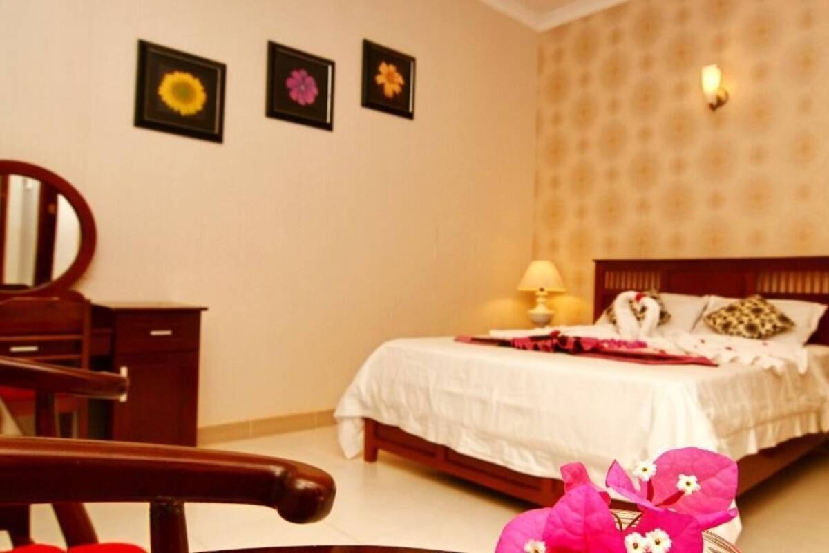 A bedroom with a bed, a nightstand, a lamp, and a mirror.