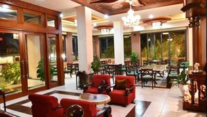 Eine geräumige Lobby mit roten Sofas, einem Couchtisch und einem Essbereich mit Holzmöbeln.