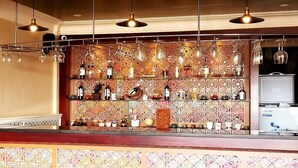Eine Bar mit dekorativer Wand, hängenden Lampen und einer Auswahl an Flaschen und Gläsern.