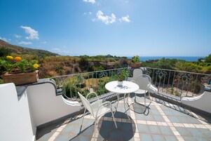 Un balcón con mesa y sillas, con vistas a un paisaje costero.