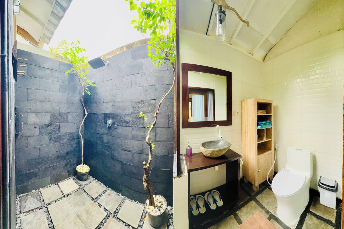 Een badkamer met een stenen wastafel, een houten kastje en een spiegel erboven.