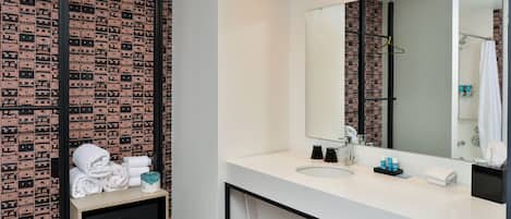 Un baño moderno con un lavamanos blanco, un espejo grande y un papel tapiz estampado.