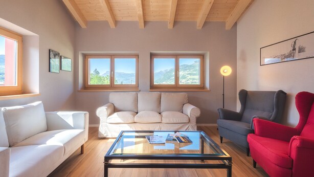 A living room with a sofa, armchairs, a glass coffee table, and two windows with a view of mountains. - Villa in the vineyards overlooking the mountains (Rovereto)