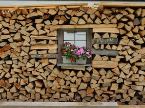 Ein Holzstapel mit einem Fenster, das Blumen zeigt.