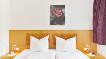 Un letto matrimoniale con lenzuola bianche, una testiera in legno con motivo decorativo, due comodini con lampade e un quadro di una rosa appeso al muro.