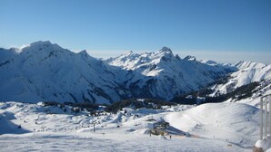 Berglandschap bedekt met sneeuw, met skipistes en een klein gebouw.