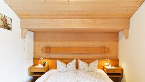Een kamer met houten lambrisering, een bed, twee nachtkastjes en een wandplank.