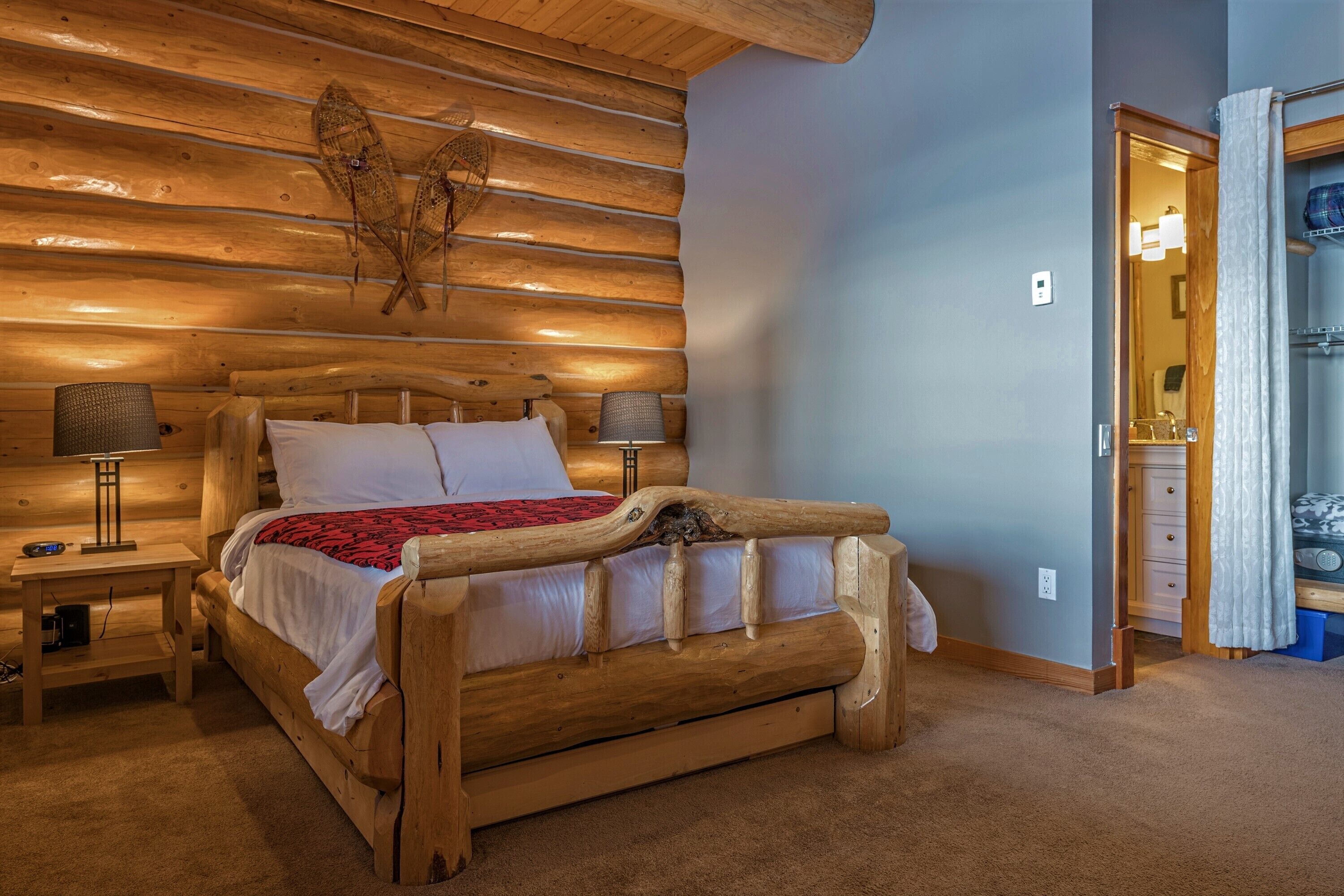 A wooden bed with a headboard, two bedside tables with lamps, and a wall-mounted fish decoration.