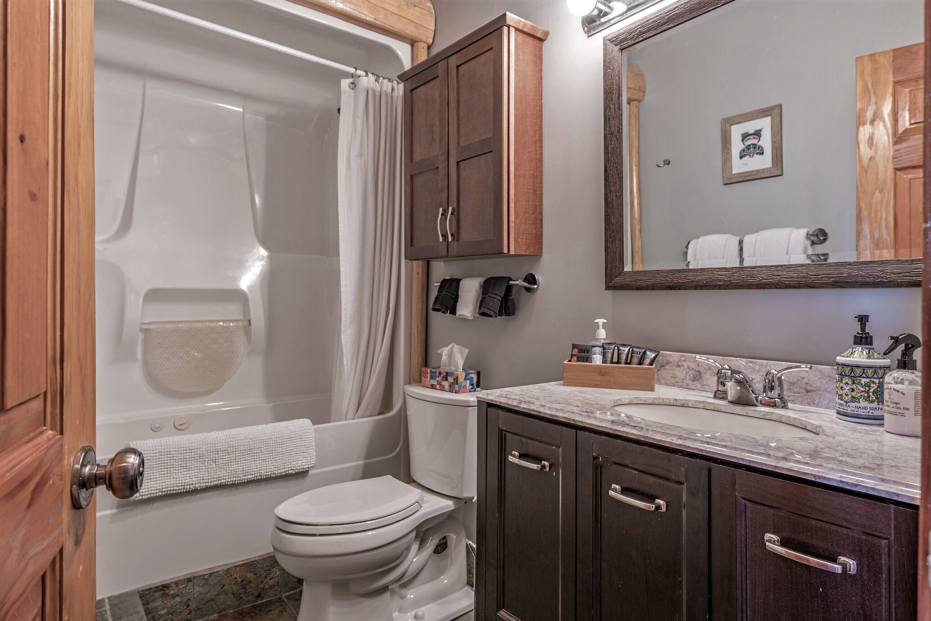 A bathroom with a bathtub, toilet, and vanity with a sink and mirror.