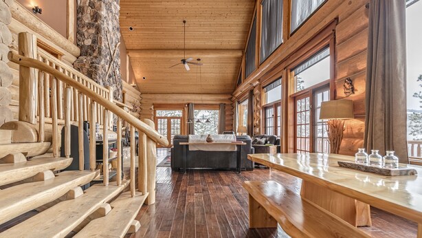 A wooden interior with a staircase, a fireplace, and a dining area. - Spirit Lodge at Silverstar (Vernon)