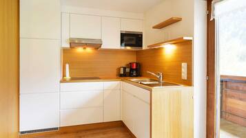 A compact kitchen with white cabinets, a microwave, a coffee maker, and a sink.